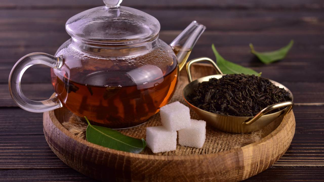 black tea in a teapot with sugar cubes