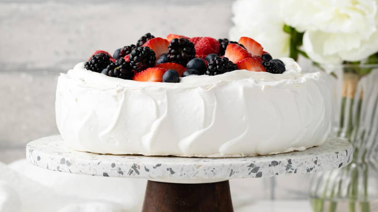 pavlova dessert on a cake stand with berries on top