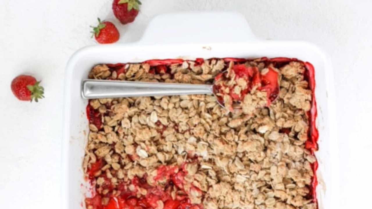 strawberry crumble in dish being dished out